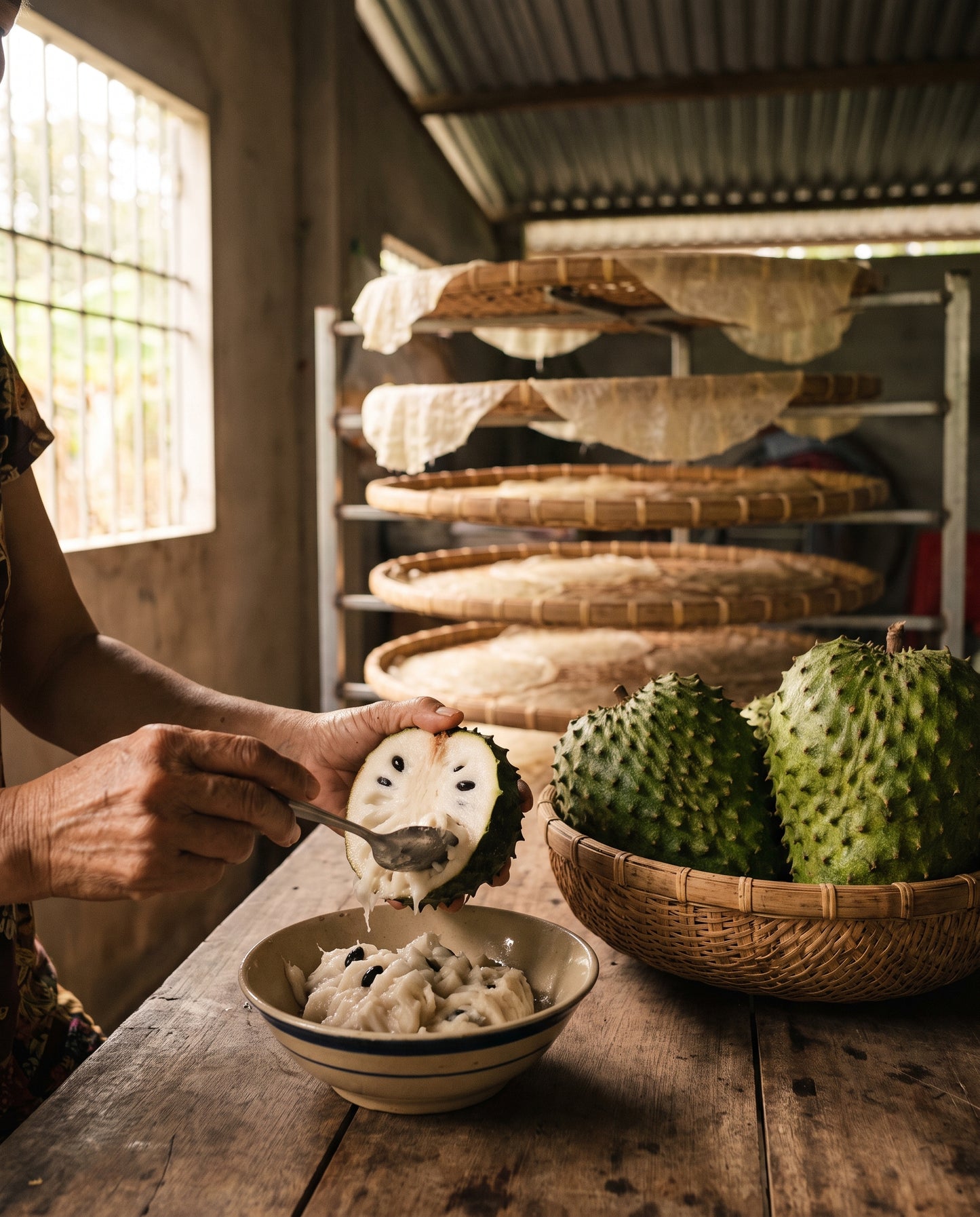Scooping fresh soursop pulp beside bamboo drying trays in the Mekong Delta