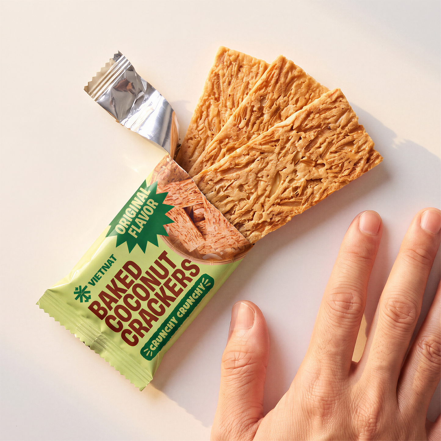 One open sachet next to a hand, showing cracker size