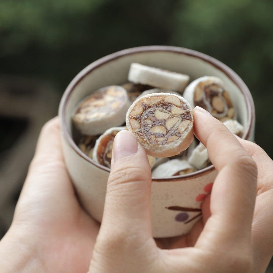 A real banana durian fruit roll held over a bowl of wrapped bites