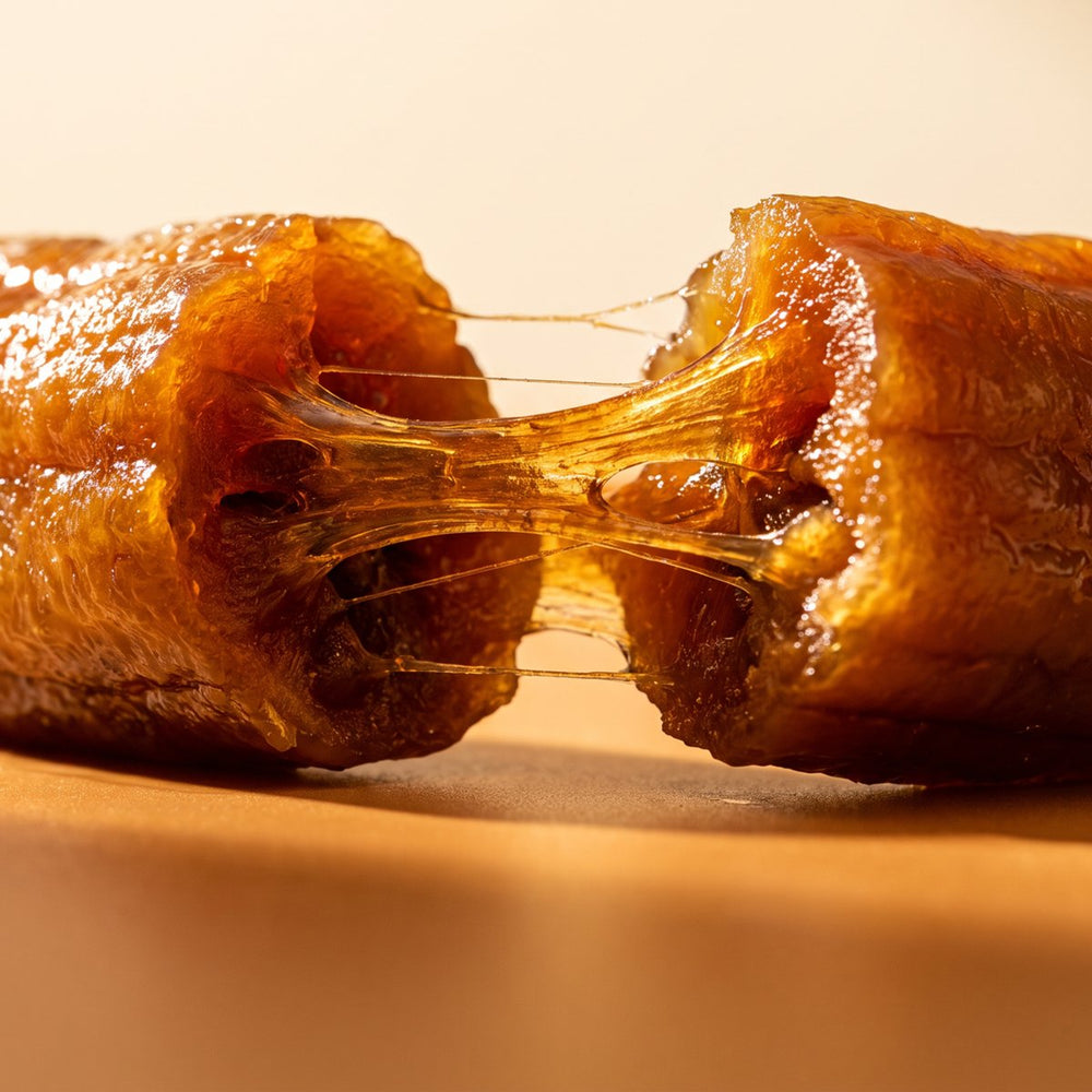 Close-up of a whole dried banana pulled apart, chewy amber texture