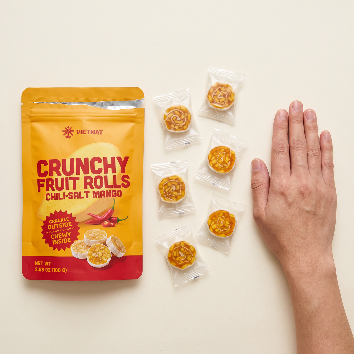 Chili-salt mango fruit rolls next to a hand to show size, about 1¼ in across