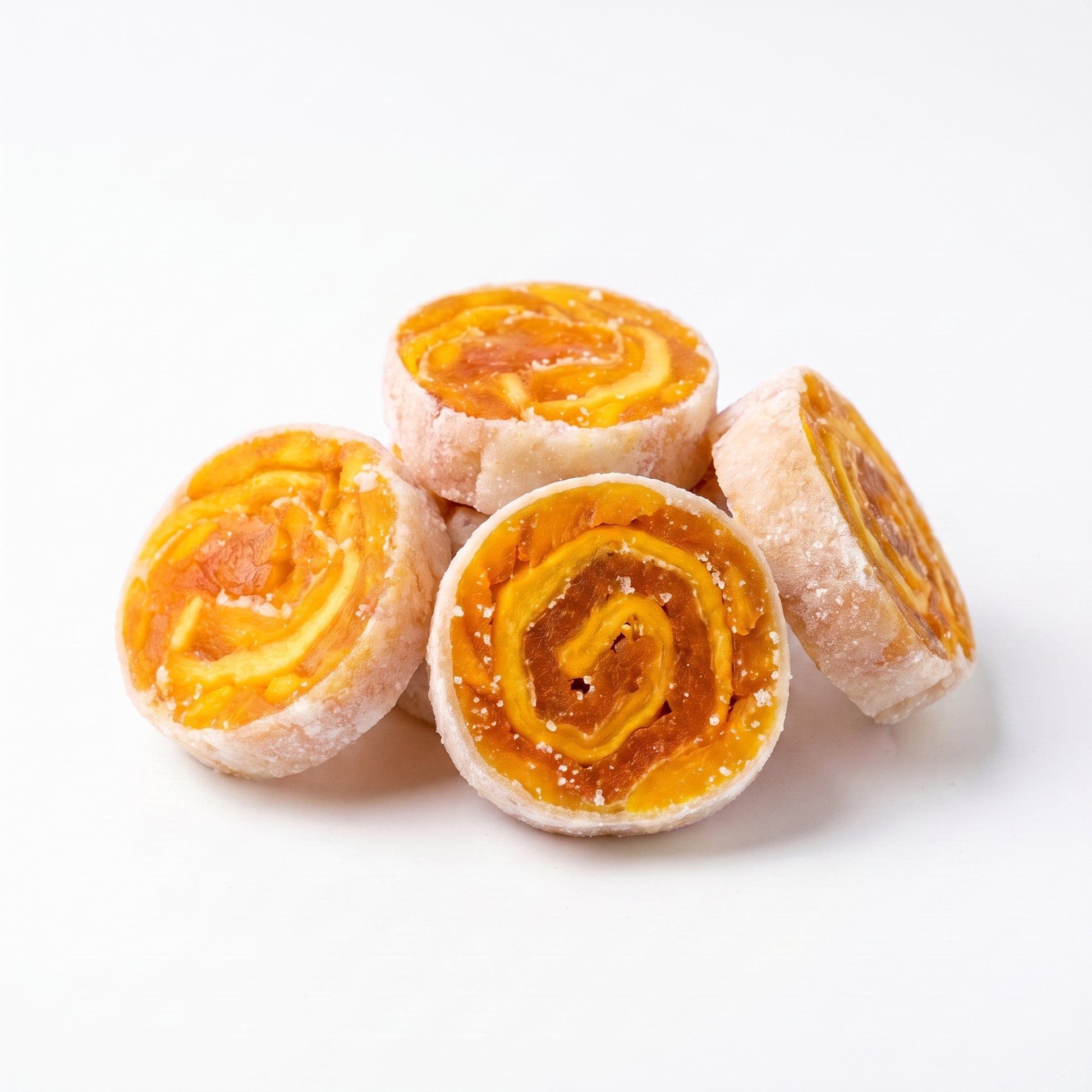 Four crispy mango fruit rolls on white, showing the rolled mango spiral