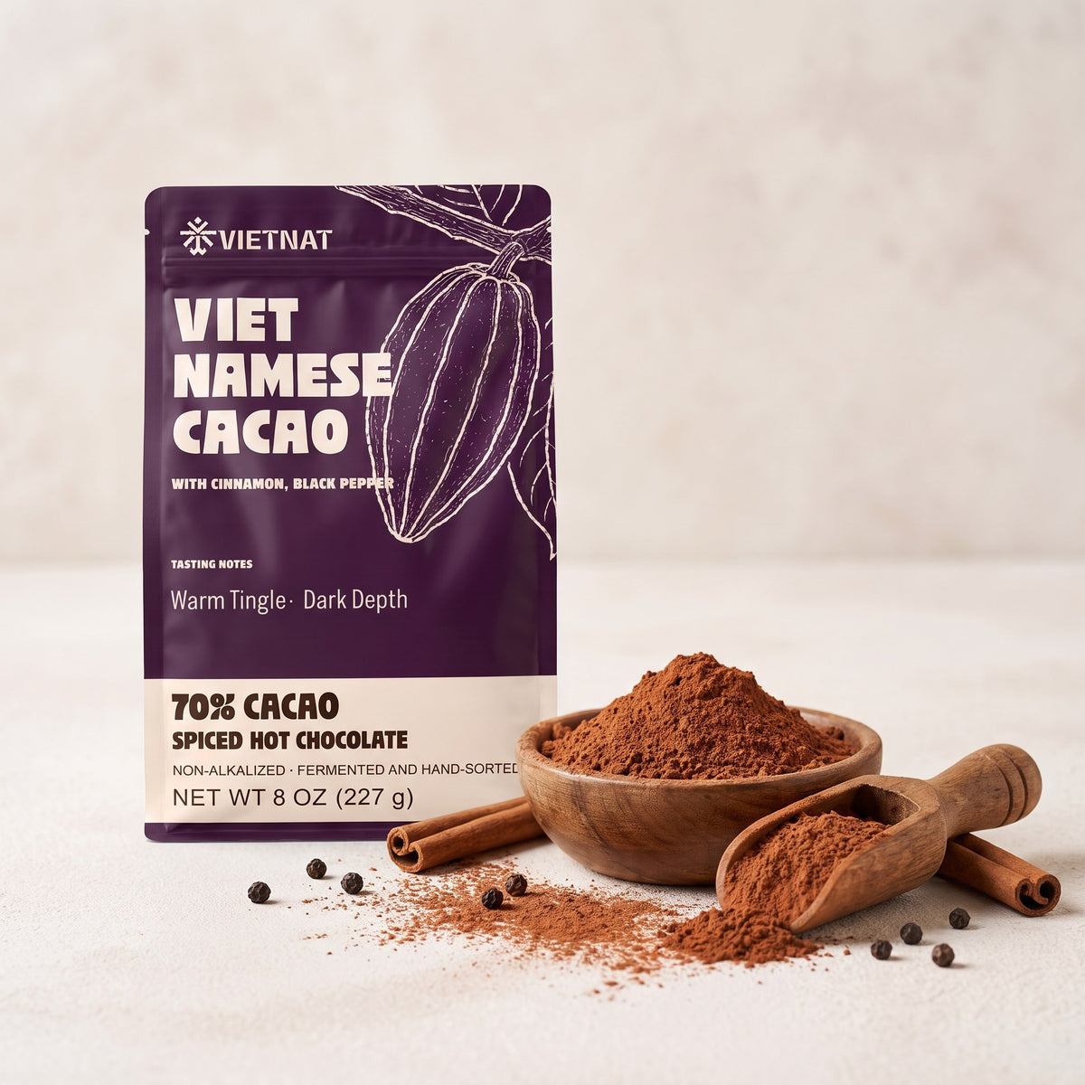 Fine cacao and spice grind in a wooden bowl beside the pouch, with cinnamon quills and black peppercorns