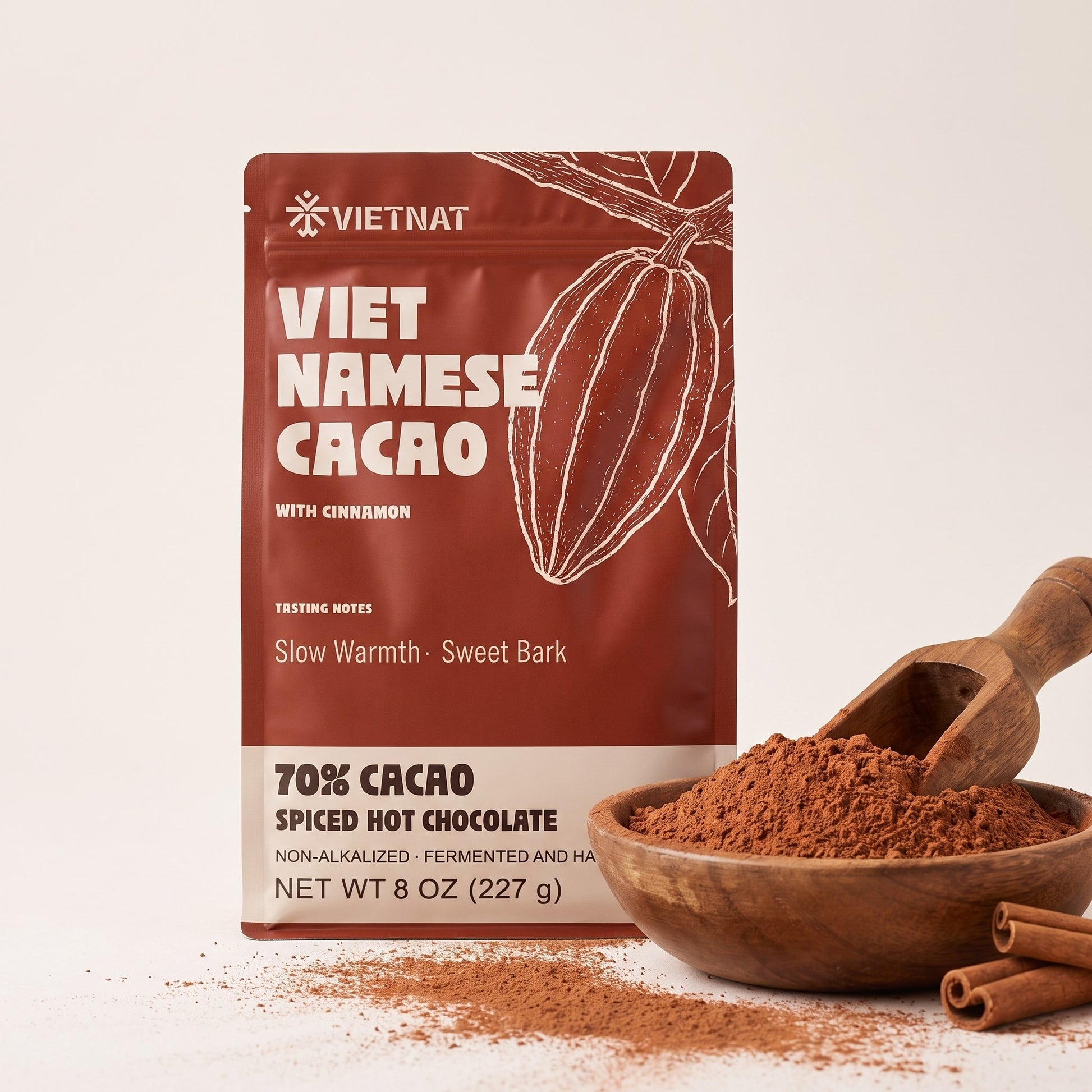 Fine cacao and cinnamon grind in a wooden bowl beside the pouch, with cinnamon quills