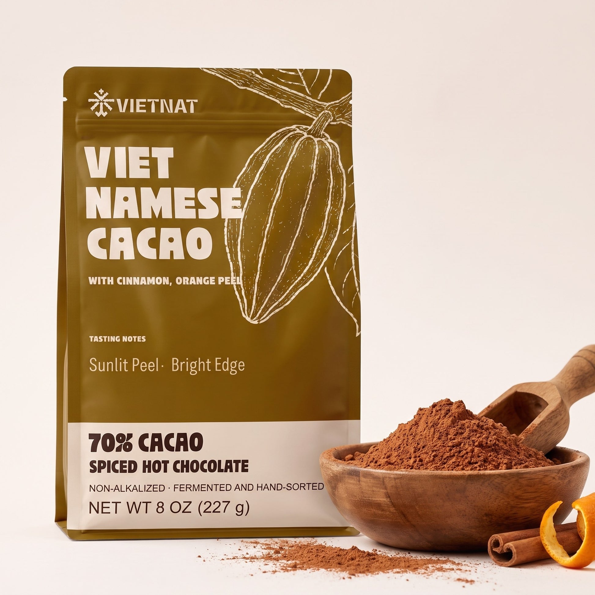 Fine cacao and spice grind in a wooden bowl beside the pouch, with cinnamon quills and dried orange peel