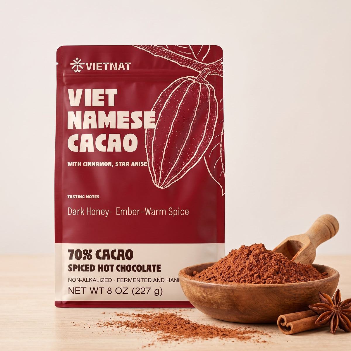 Fine cacao and spice grind in a wooden bowl beside the pouch, with cinnamon quills and star anise